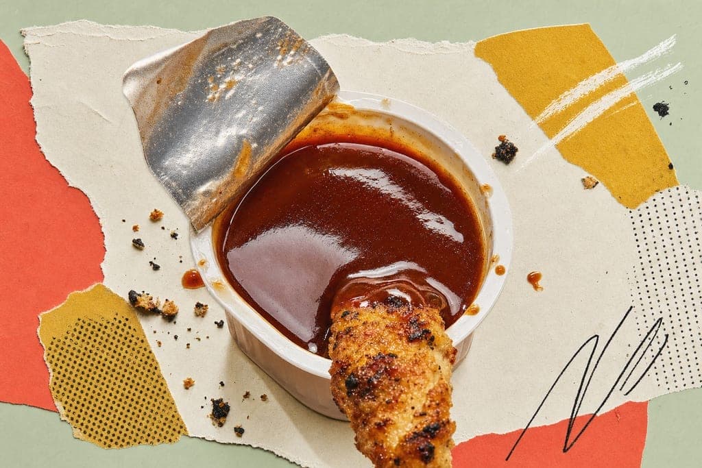 Editorial mixed-media collage of a small open dipping sauce cup as the unmistakable central subject, viewed from a dramatic ultra-close macro three-quarter angle slightly above rim level, centered on a clean pale cream torn-paper field atop a soft sage-green tabletop setting at bright fresh midday light, the sauce a glossy smoky honey-barbecue tone with a gentle reflective sheen and one grilled chicken nugget corner just barely dipping into the surface from the lower edge of frame, surrounded by a subtle ring of tiny sauce drips and a few scattered char-speck crumbs for calorie-conscious fast-food context, composition airy and minimal with bold coral and muted mustard paper shapes offsetting the neutral background, energetic yet polished mood, appetizing, modern, crisp, warm, inviting, no characters, no text, no humans.